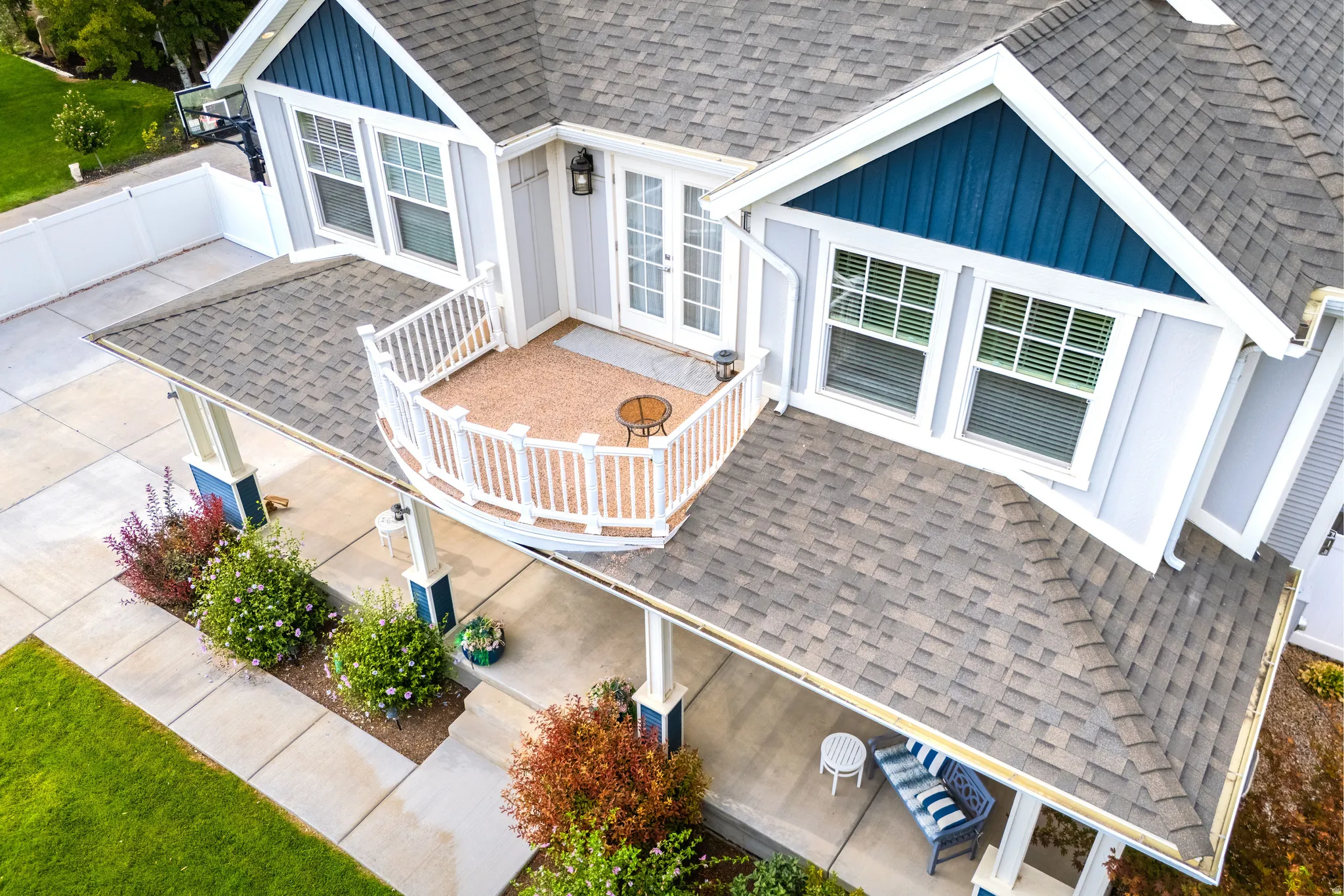 Light gray siding with blue accent gables, asphalt shingle roofing, and a second-story balcony with white railing