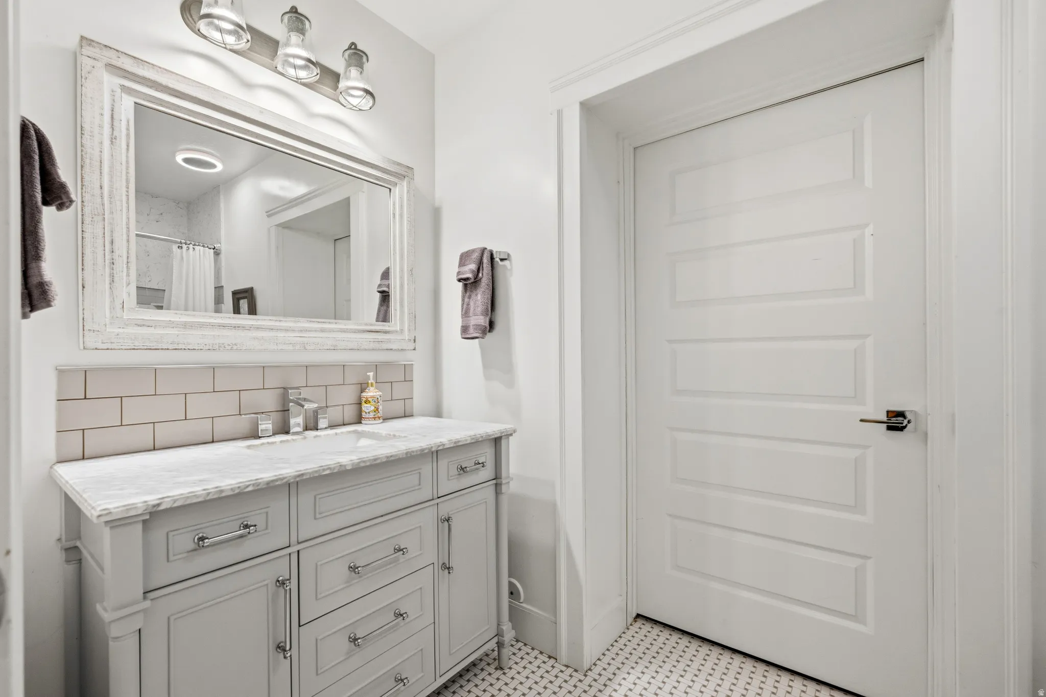 Vanity with a light gray finish, a rectangular undermount sink, and a stone-finish countertop