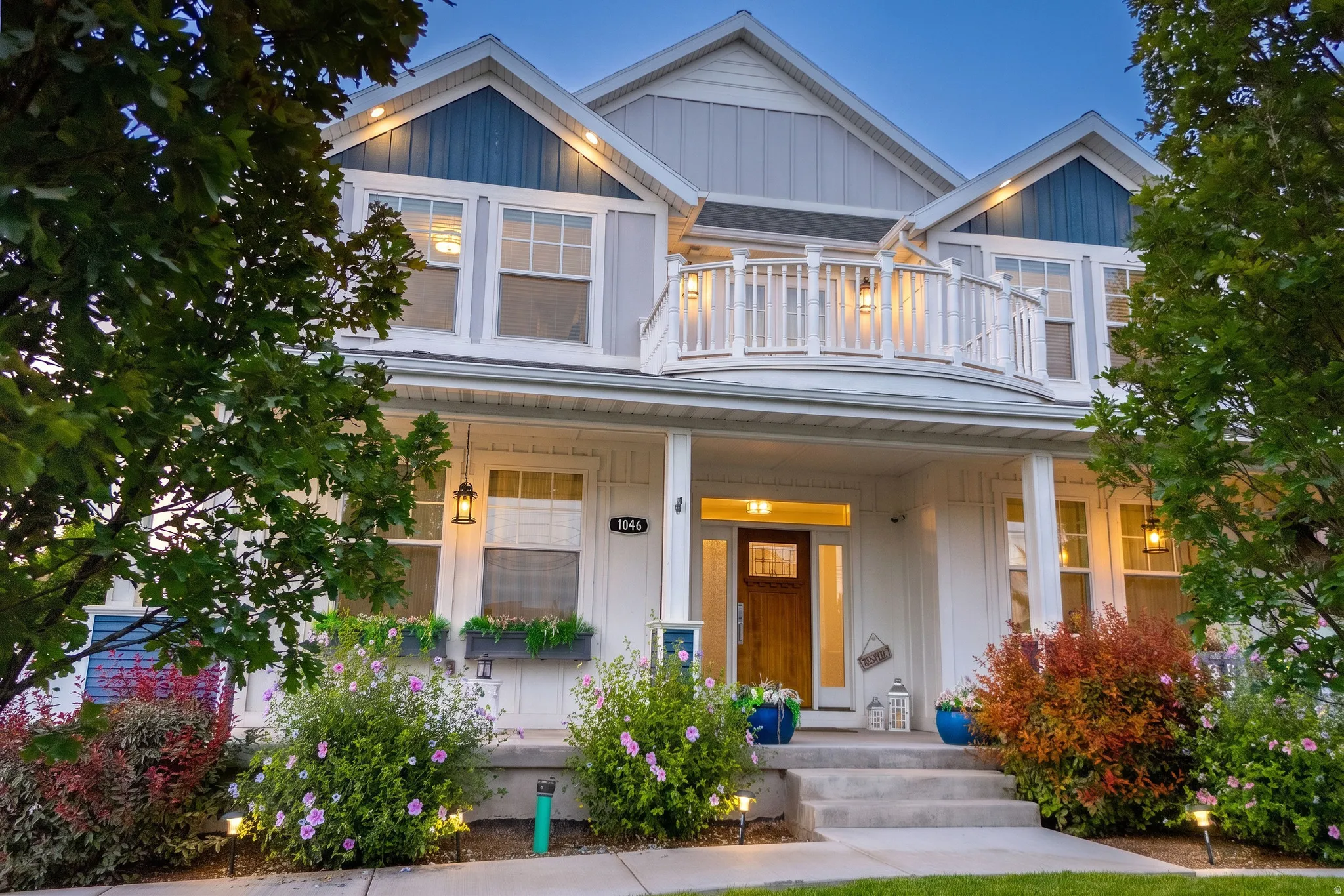 Multi-level exterior with a second-story balcony, covered porch, and mature landscaping