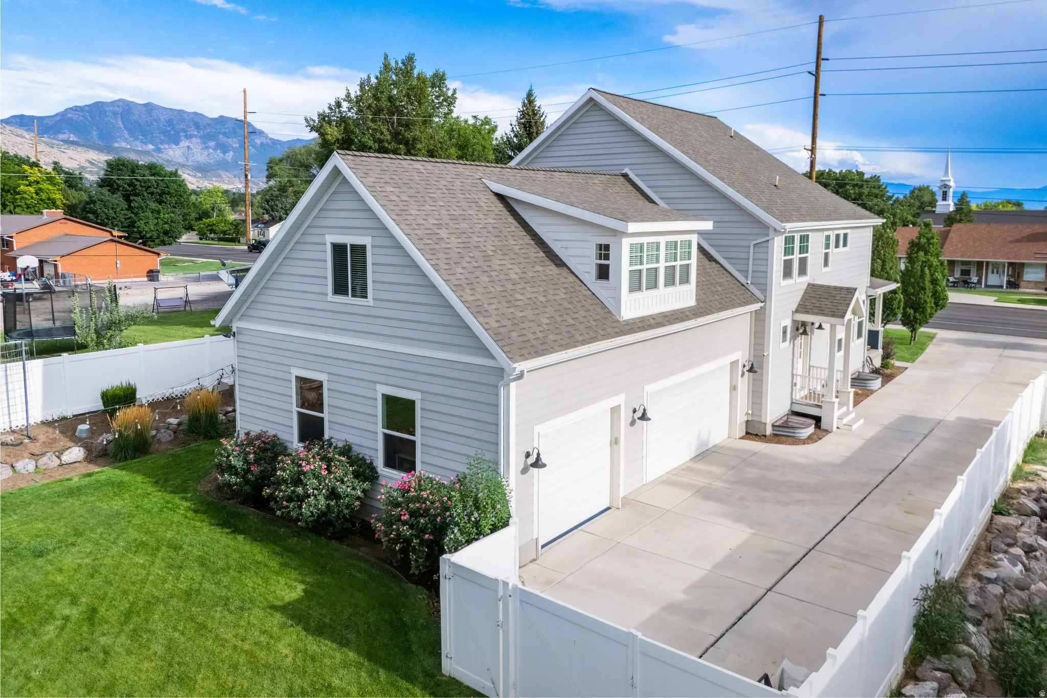 Two-story residence featuring light gray siding, a prominent two-car garage, and a covered front entry