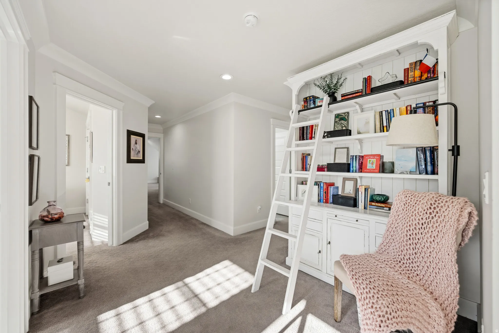 Built-in shelving unit with ladder, recessed ceiling lighting, crown molding, and carpeted flooring