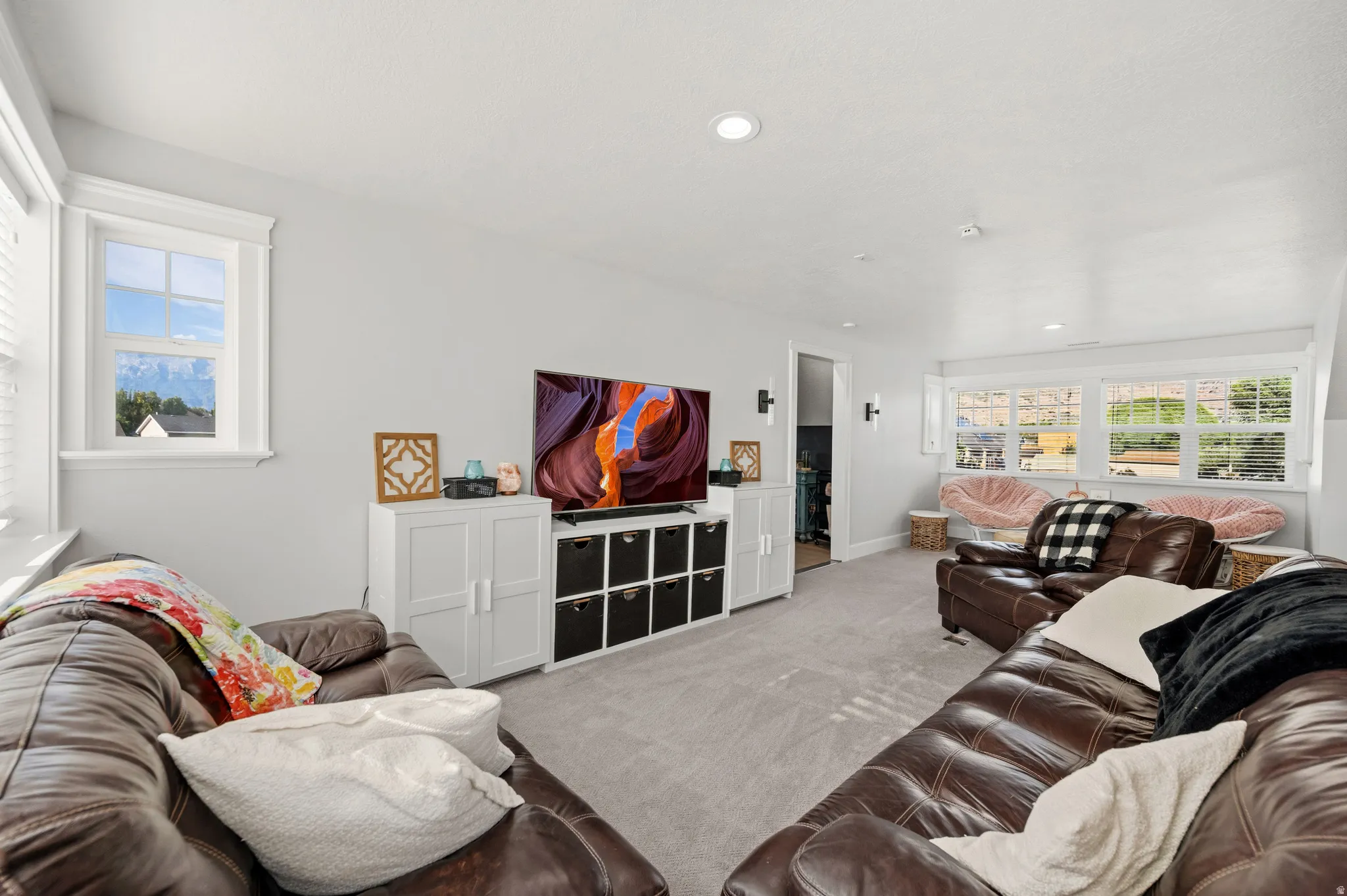 Carpeted recreation room featuring recessed lighting, multiple windows, and built-in storage cabinetry