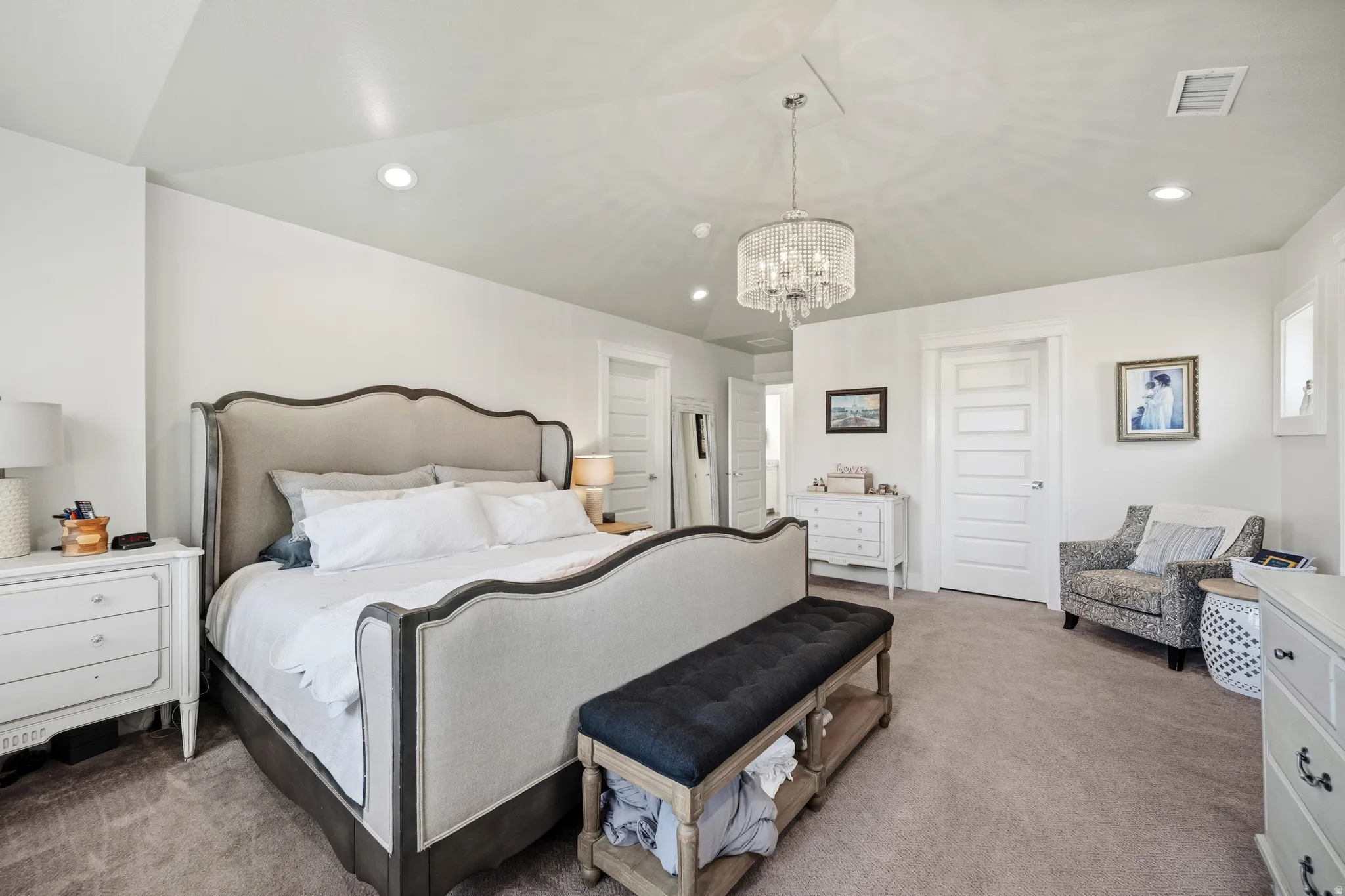 Vaulted ceiling with a contemporary chandelier, recessed lighting, and soft gray carpeting
