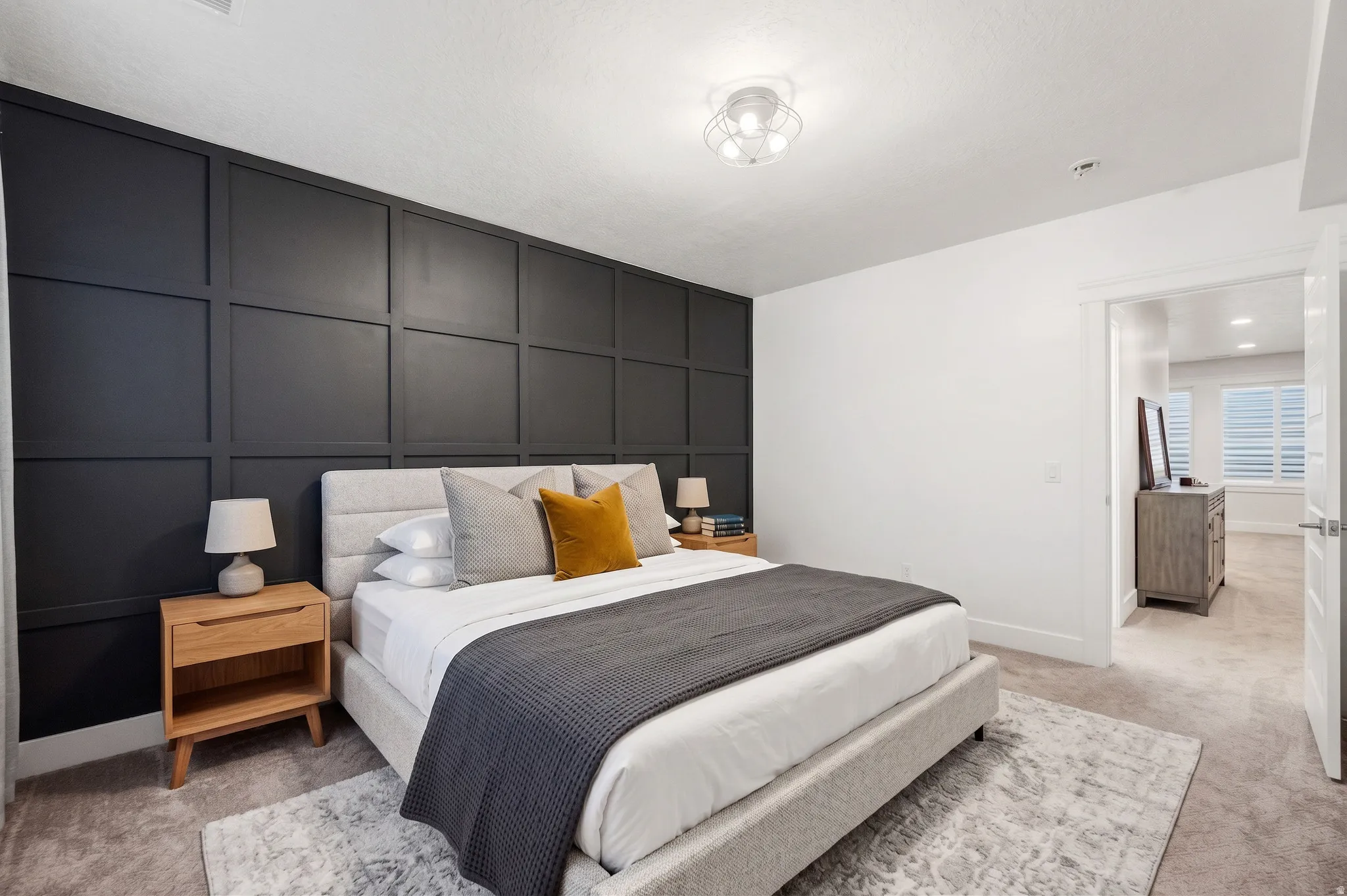 Accent wall with wainscoting detail, ceiling-mounted light fixture, and neutral carpeting