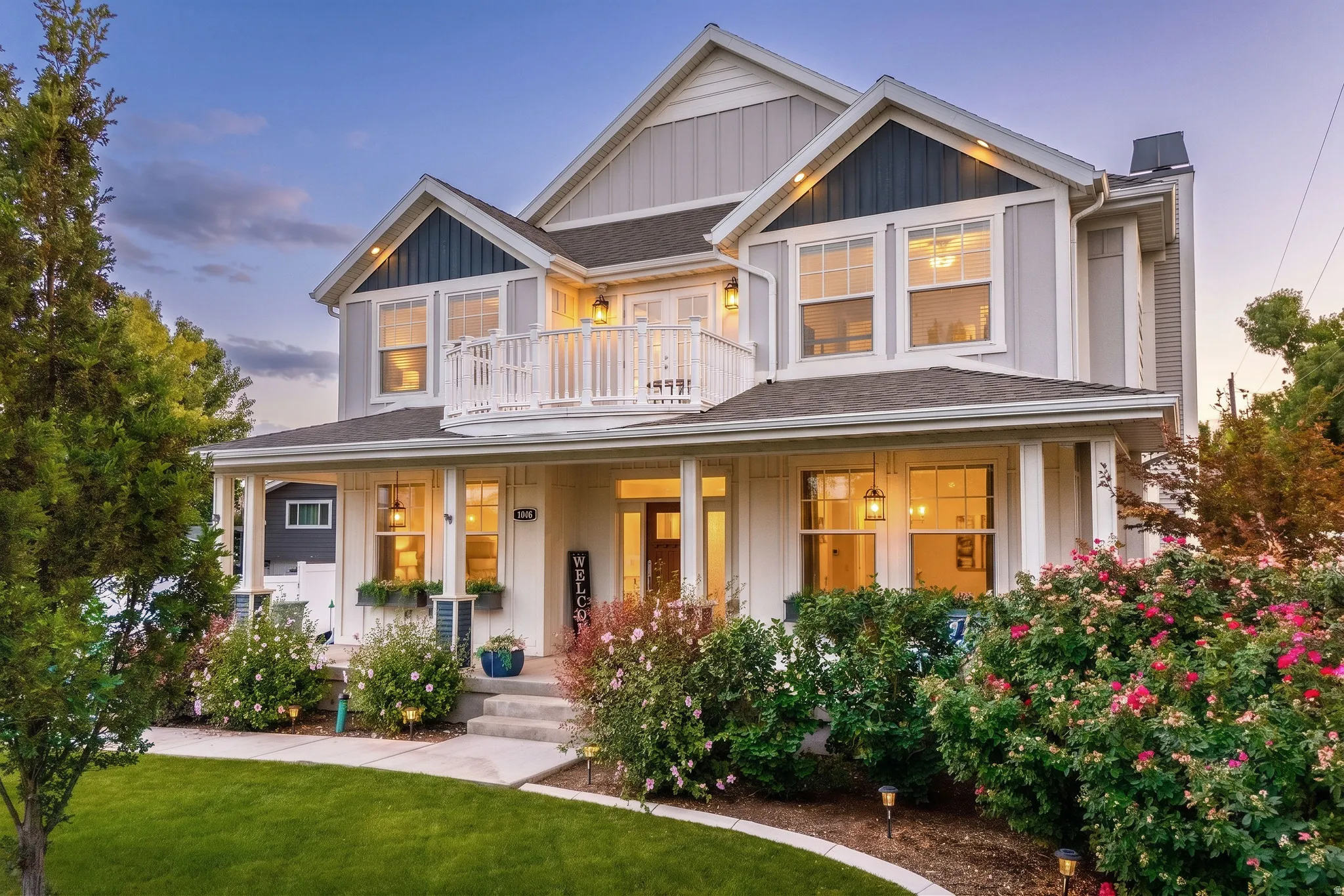 Two-story residence featuring light gray siding, dark trim accents, and a covered front porch with white columns