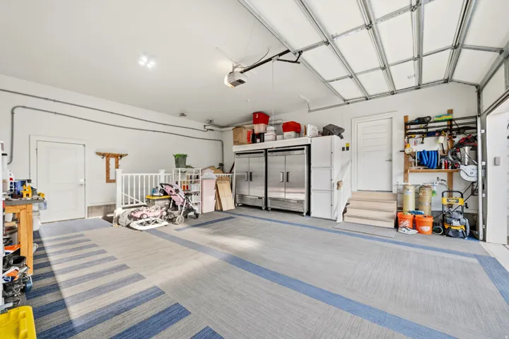 Attached garage with a white paneled door, light-colored walls, and striped flooring