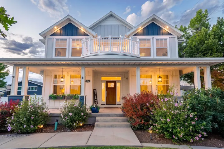 Crafted exterior featuring a covered front porch, prominent entryway, second-story balcony with balustrade, and integrated landscaping