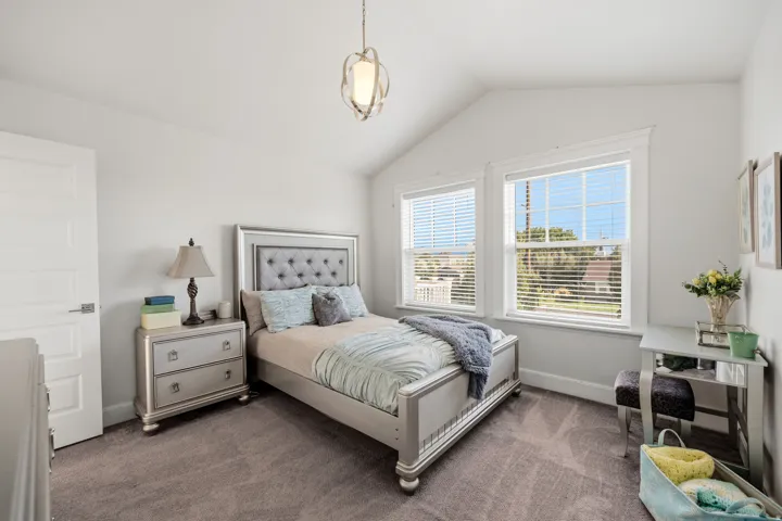 Vaulted ceiling, two pane windows, recessed window frames, neutral wall color, and carpeted flooring