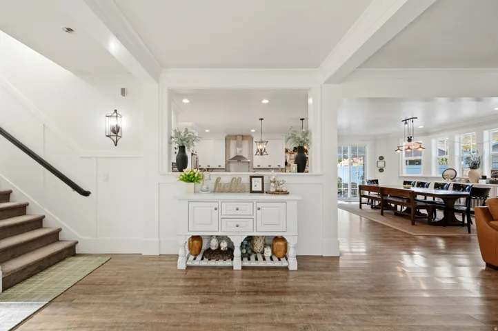 Wood-finish flooring throughout, white paneled walls, and a staircase with a dark handrail