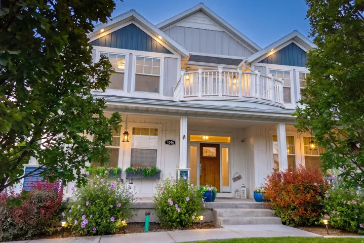 Multi-level exterior with a second-story balcony, covered porch, and mature landscaping