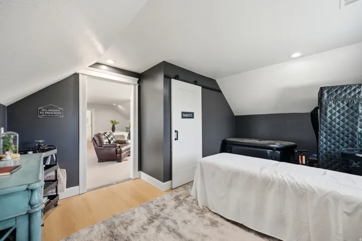 Sloped ceiling design, recessed lighting, wood-finish flooring, barn door entry, and dark accent walls