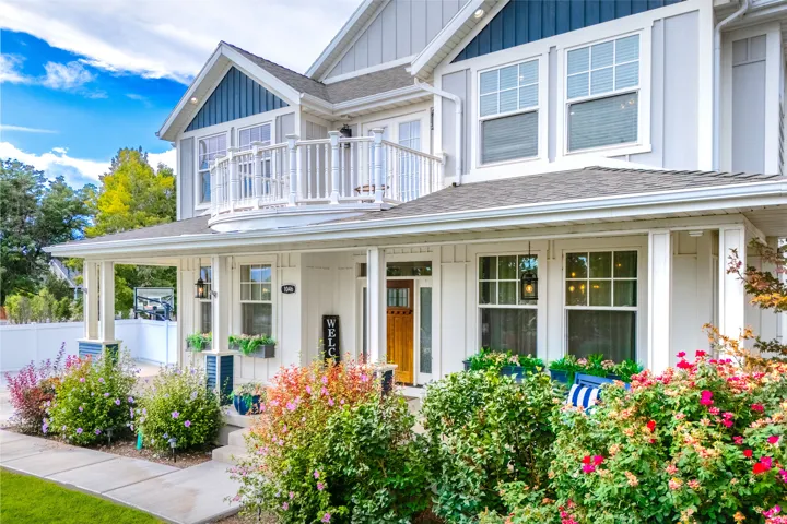 Two-story exterior with board and batten siding, second-level balcony, covered front porch, and mature landscaping