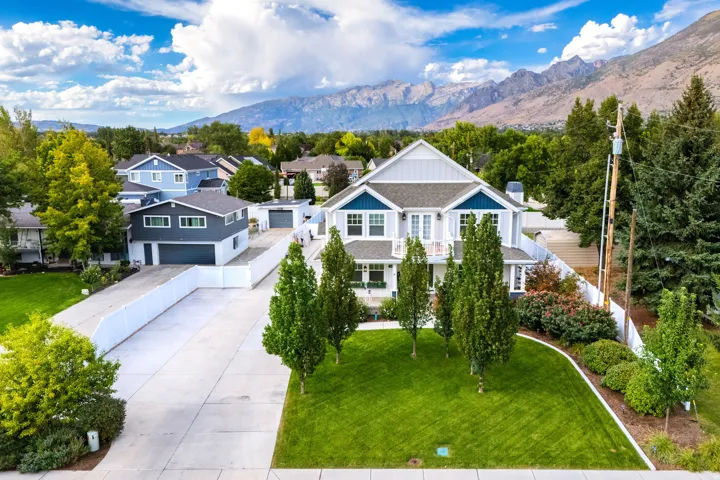 Two-story residence with a light gray and blue exterior, featuring a prominent front lawn and mountain backdrop