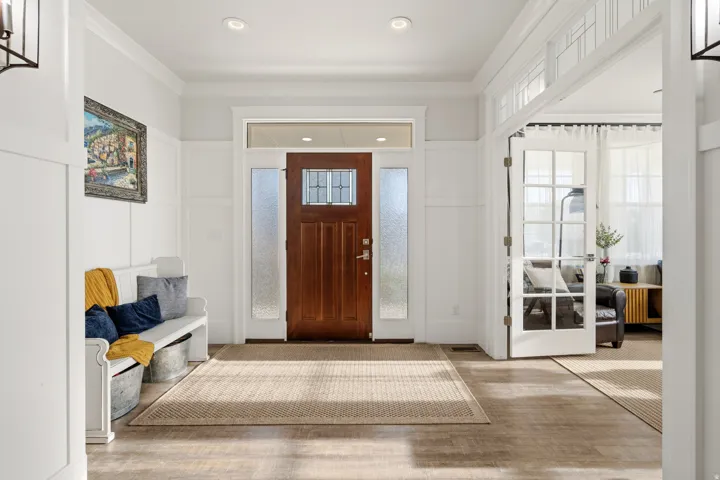 Wood-finish flooring throughout, featuring a rich wood entry door with glass panels