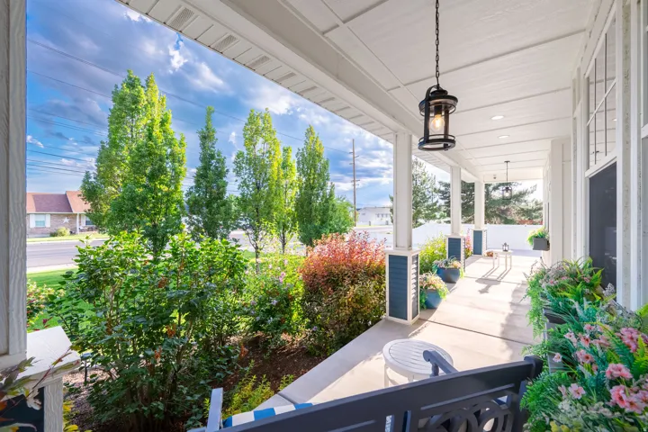 Expansive covered porch with white columns, concrete flooring, and suspended pendant lighting