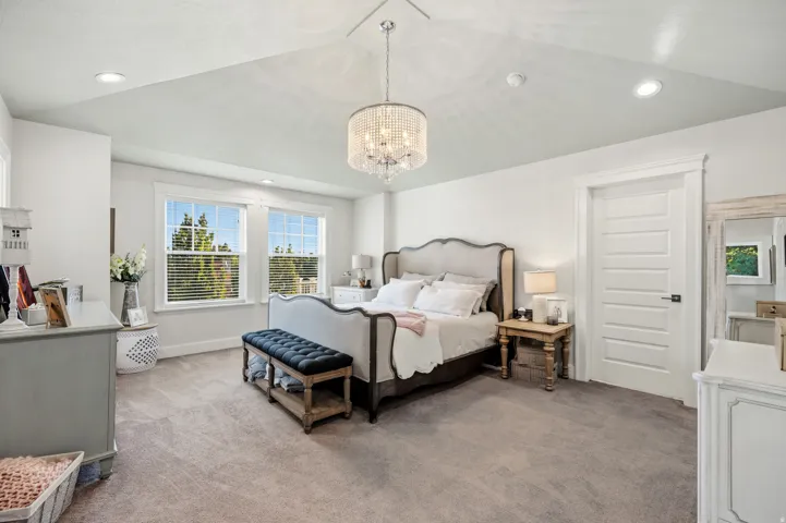 Recessed lighting, vaulted ceiling, decorative chandelier, paneled interior door, and dual windows with blinds