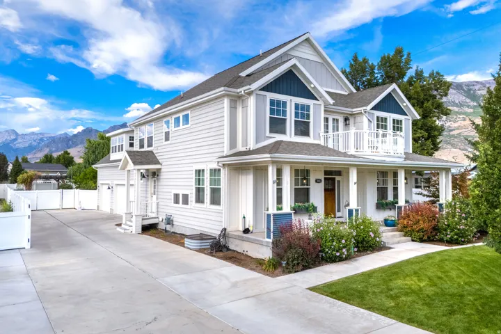 Two-story residence featuring light-colored siding, a covered porch with white columns, a second-story balcony with white railings, and an attached two-car garage