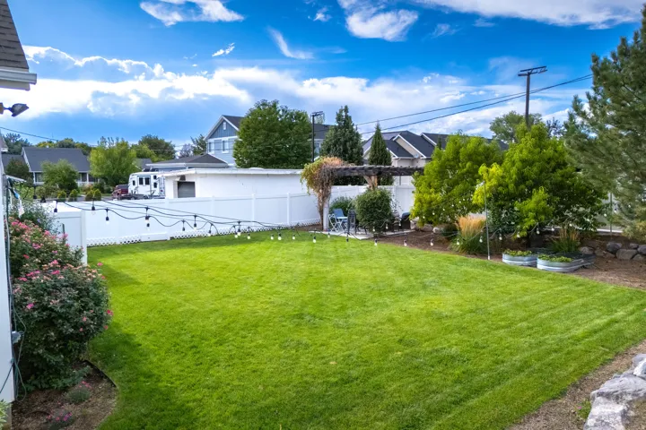 Expansive green lawn, white privacy fencing, and mature perimeter trees