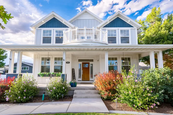 Two-story residence featuring a covered front porch, an upper-level balcony with white railing, and a wood-finish entry door with sidelights