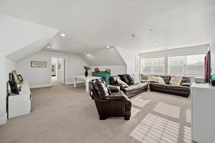 Expansive carpeted room with multiple windows, recessed lighting, and sloped ceiling details