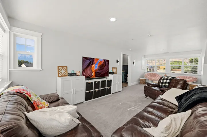 Carpeted recreation room featuring recessed lighting, multiple windows, and built-in storage cabinetry