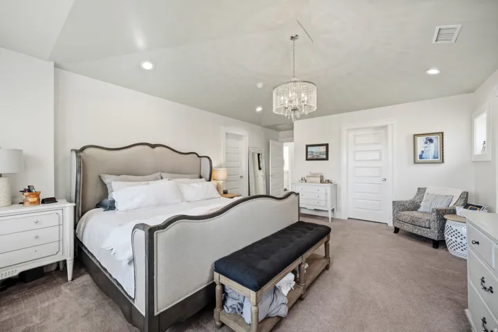 Vaulted ceiling with a contemporary chandelier, recessed lighting, and soft gray carpeting