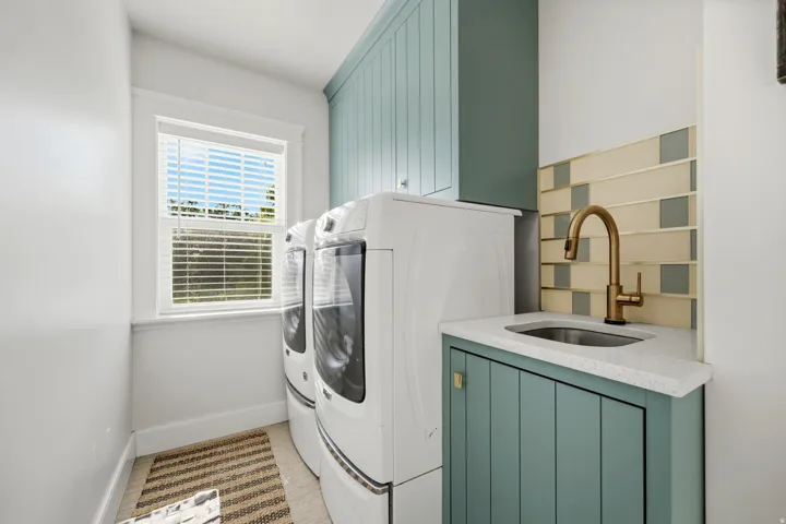 Dedicated utility space featuring a built-in sink with a gooseneck faucet, light-toned countertop, custom cabinetry, and a decorative tile backsplash