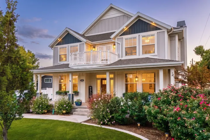 Two-story residence featuring light gray siding, dark trim accents, and a covered front porch with white columns