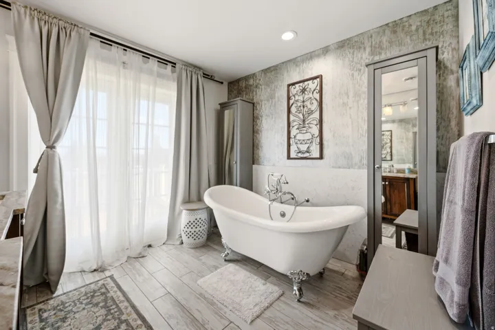 Freestanding clawfoot bathtub with chrome fixtures, wood-finish flooring, half-wall wainscoting, a full-length mirror cabinet, and recessed ceiling lighting