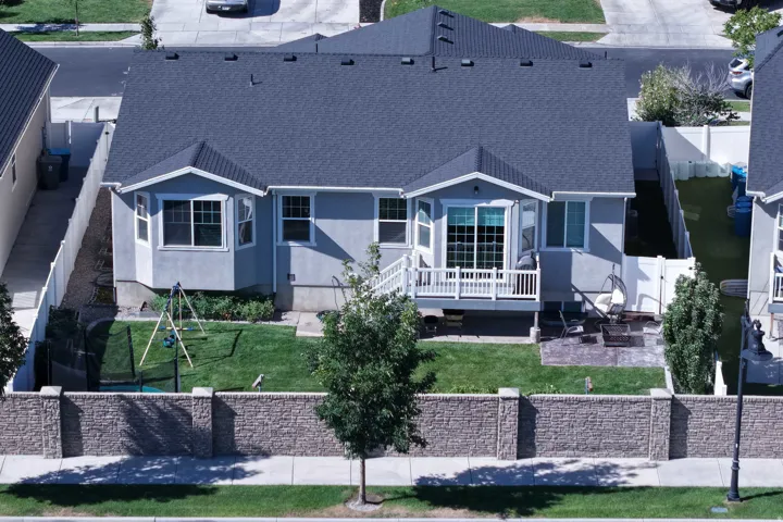 Well-maintained backyard featuring a manicured lawn, stone patio, and a private deck