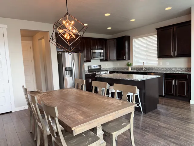 Modern open-concept layout with wood-finish flooring, dark wood cabinetry, and stainless steel appliances