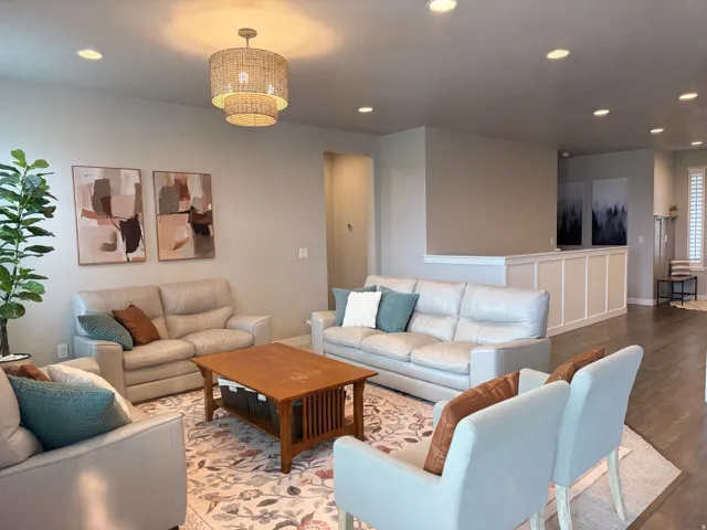 Recessed lighting, a tiered woven light fixture, light gray wall paint, dark wood-finish flooring, and white wainscoting