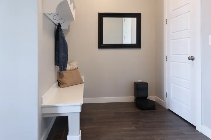 Built-in bench seating with coat hooks, wood-finish flooring, and a contemporary five-panel door