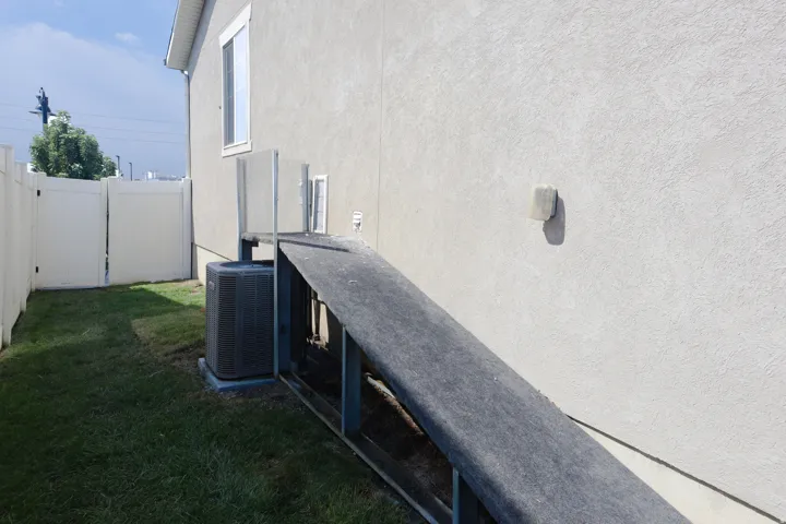 Stucco exterior with a white vinyl fence and a lawn area