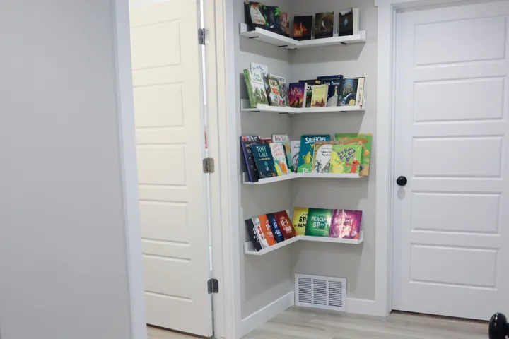 Built-in corner shelving, light wood-finish flooring, and paneled doors
