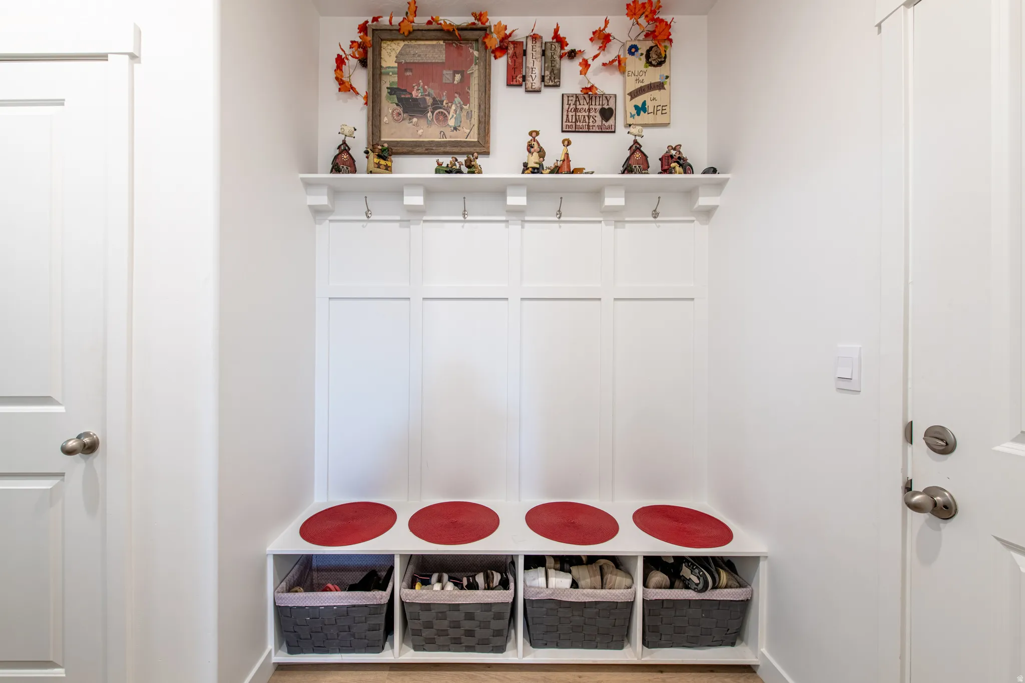 Built-in white storage bench with integrated shelving, upper hooks, and a display shelf