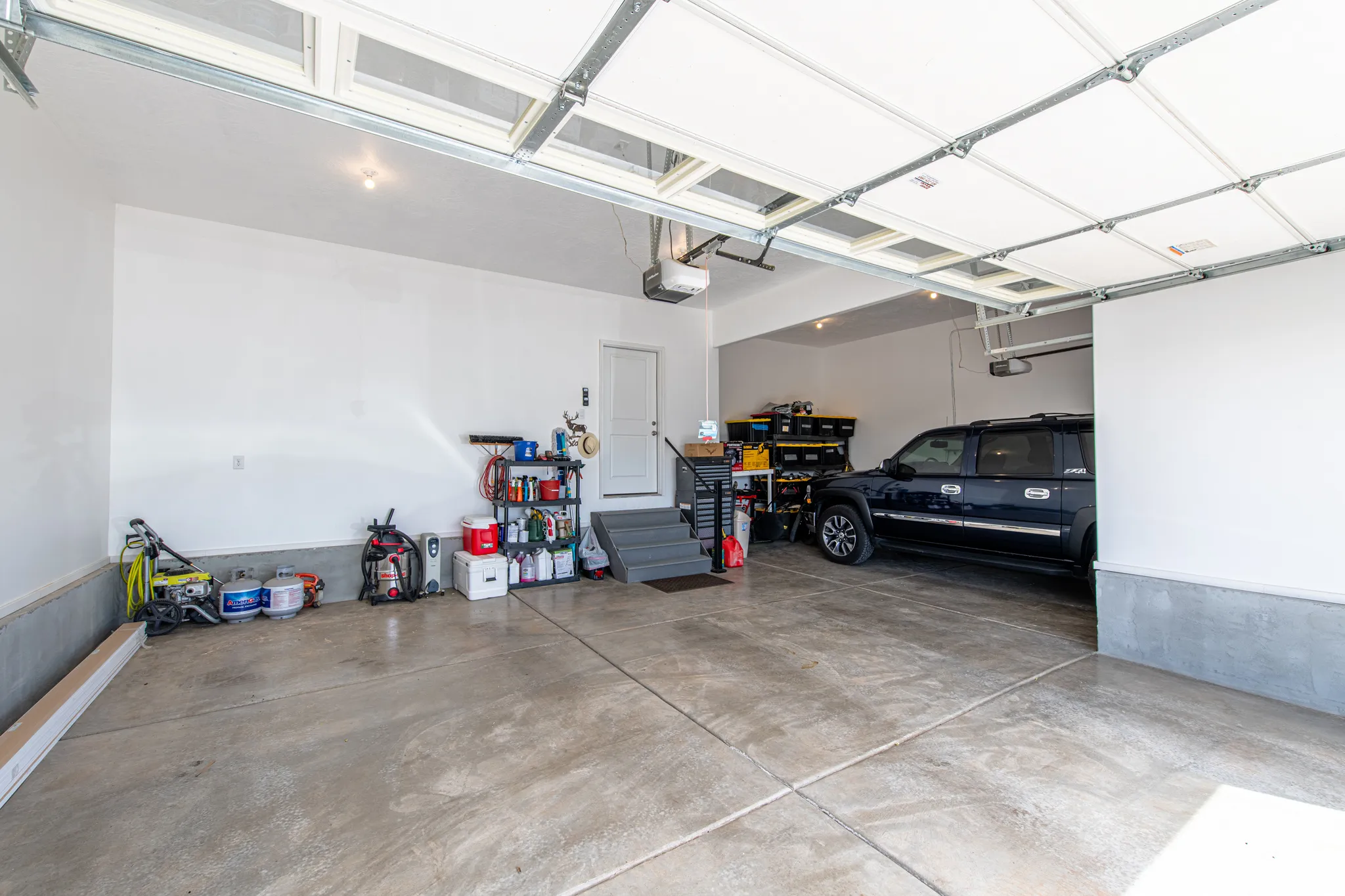 Spacious garage with concrete flooring, automatic garage door openers, and a separate utility area