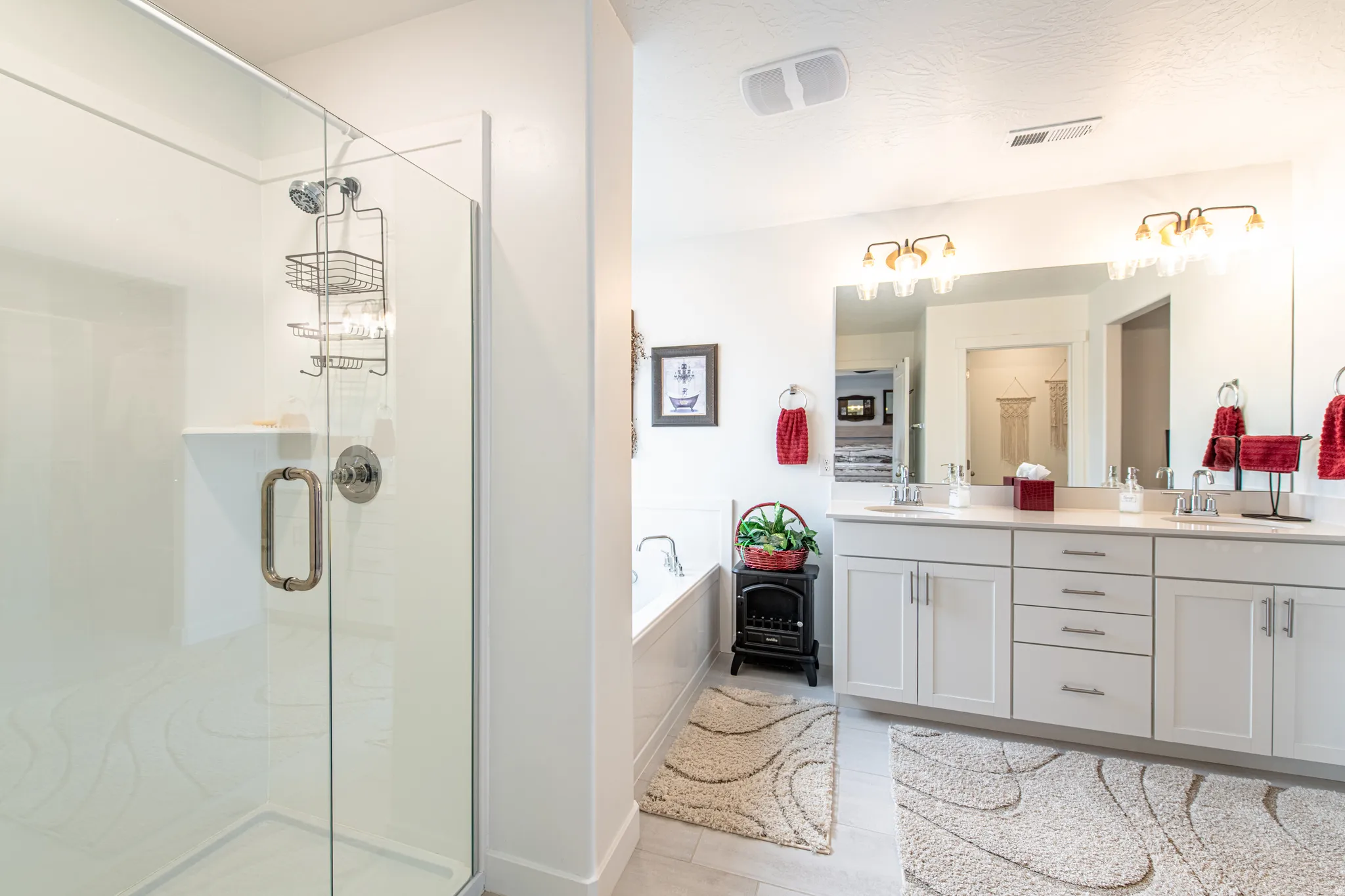 Glass-enclosed shower with a built-in shelf, dual vanity with a large mirror, light-toned cabinetry, and a built-in soaking tub