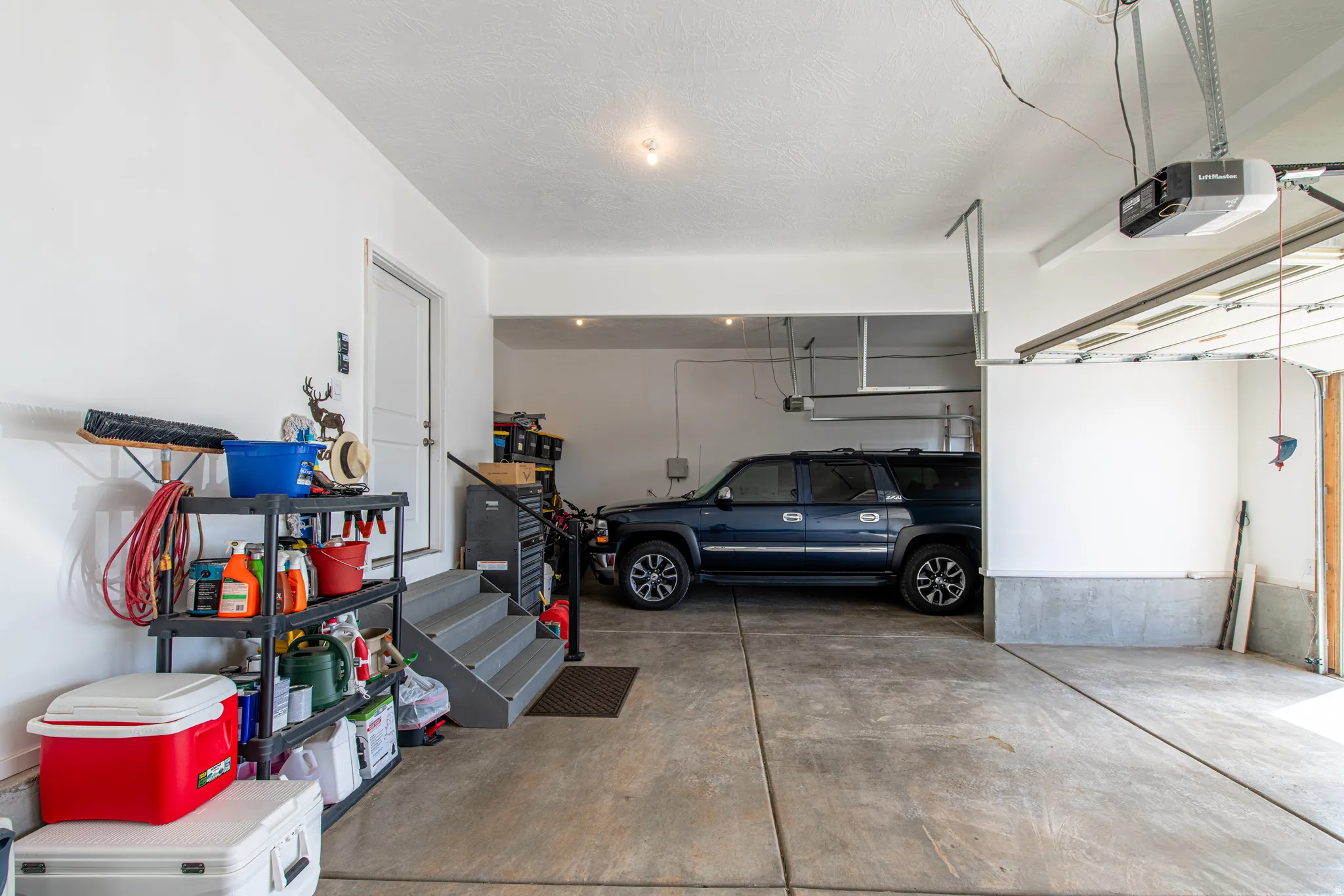 Attached garage featuring a concrete floor, white painted walls, and an automatic garage door opener