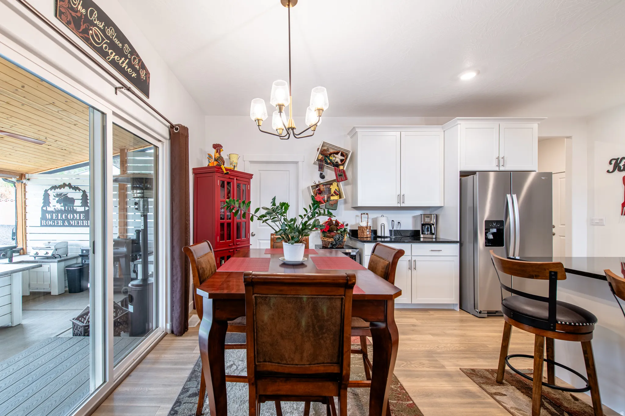 Kitchen dining area featuring wood-finish flooring, white cabinetry, dark countertops, and stainless steel appliances