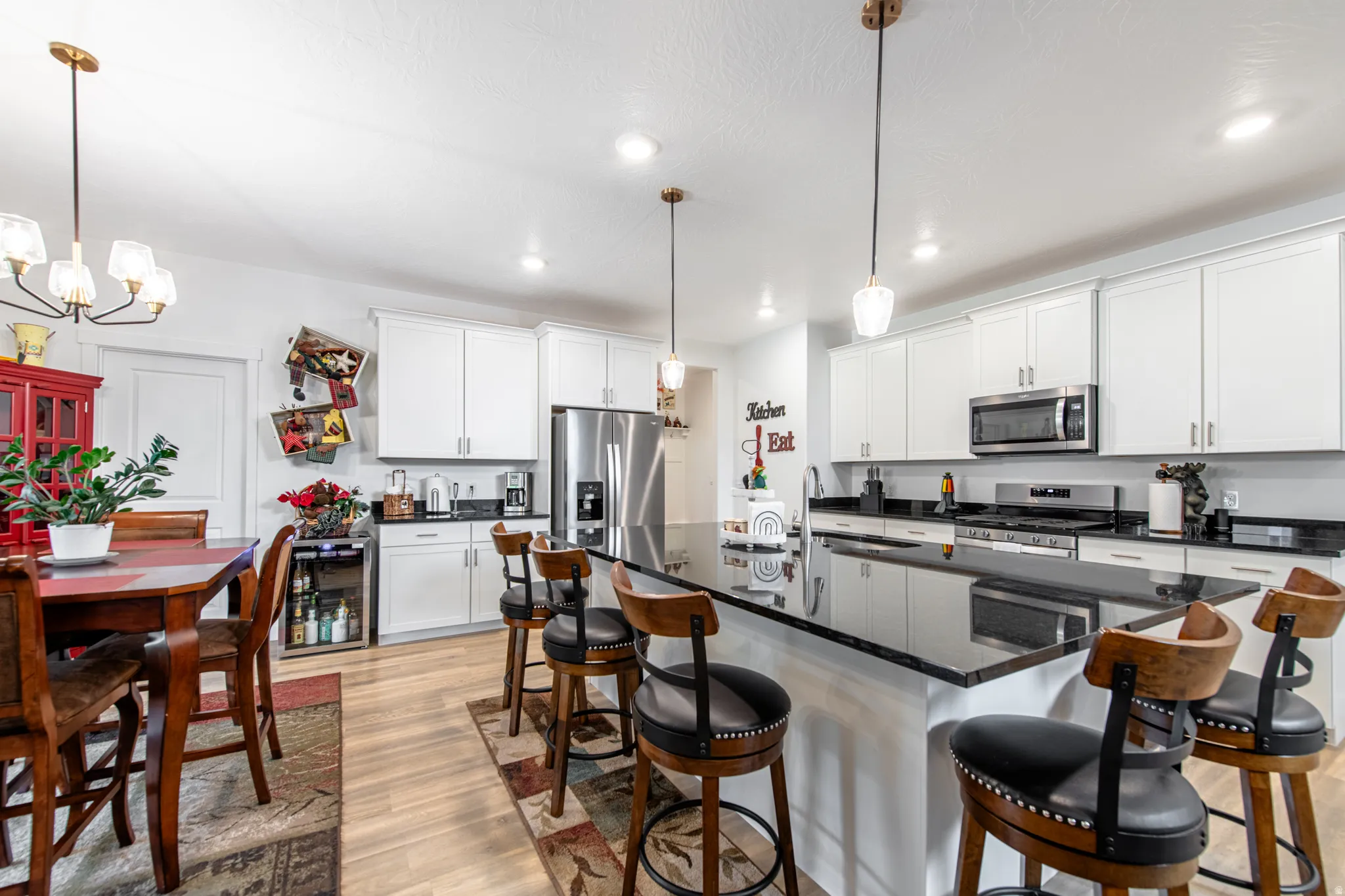 Kitchen featuring white cabinetry, black countertops, stainless steel appliances, and wood-finish flooring