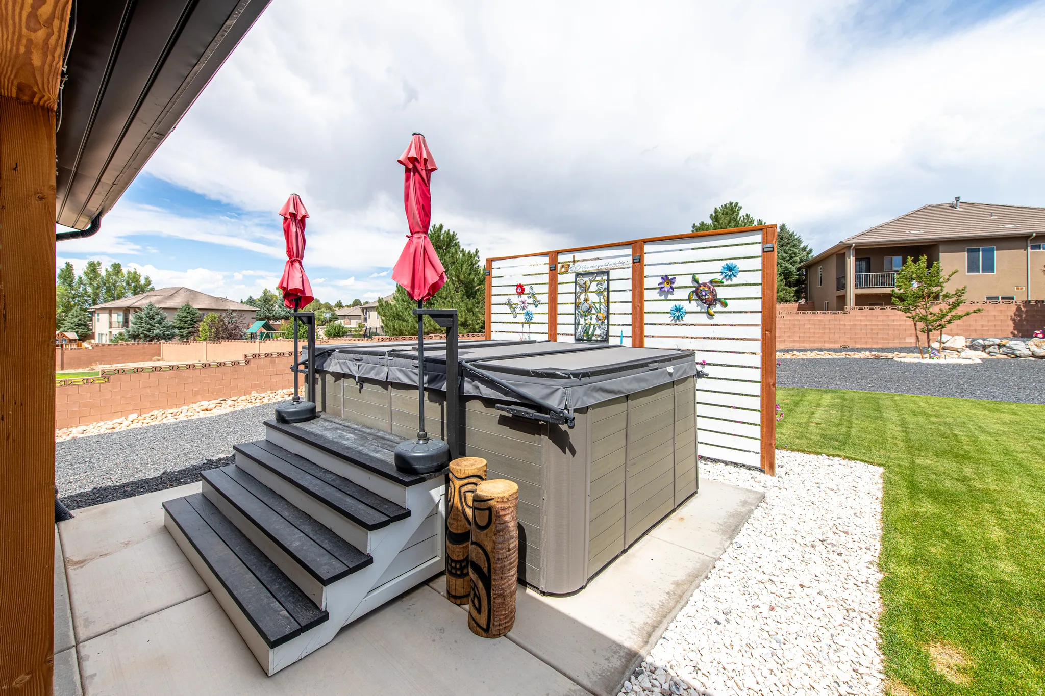 Hardscaped patio featuring a hot tub with steps, privacy screen, and an adjacent lawn area