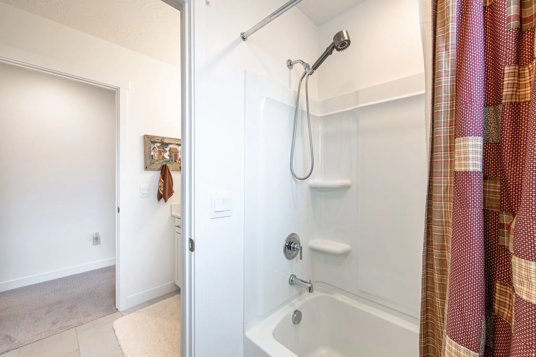 White tub/shower combination with a chrome shower head and built-in shelving