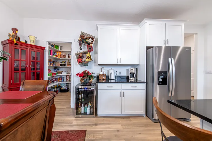 White cabinetry with dark countertops, stainless steel French door refrigerator, wood-finish flooring, and a walk-in pantry