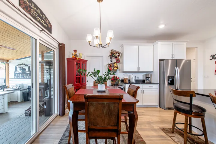Kitchen dining area featuring wood-finish flooring, white cabinetry, dark countertops, and stainless steel appliances