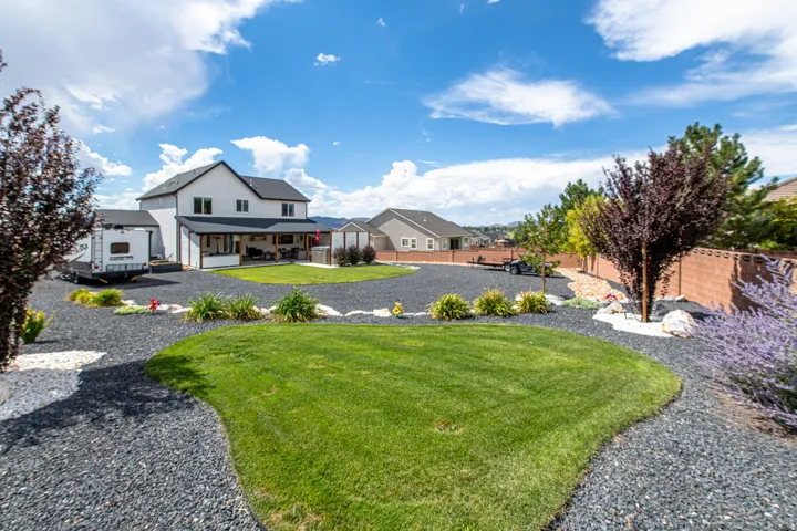 Expansive gravel-covered yard with a manicured central lawn, established trees, and a low brick perimeter wall