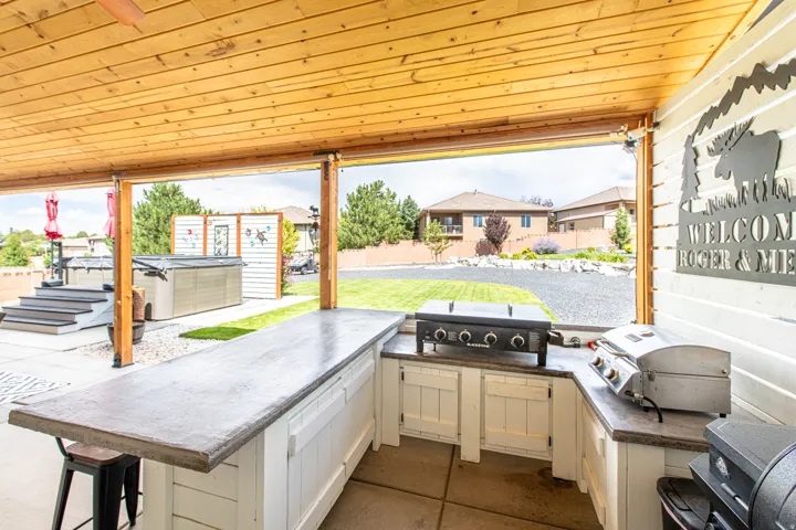 Outdoor kitchen featuring a built-in grill, concrete countertops, and wood-paneled ceiling