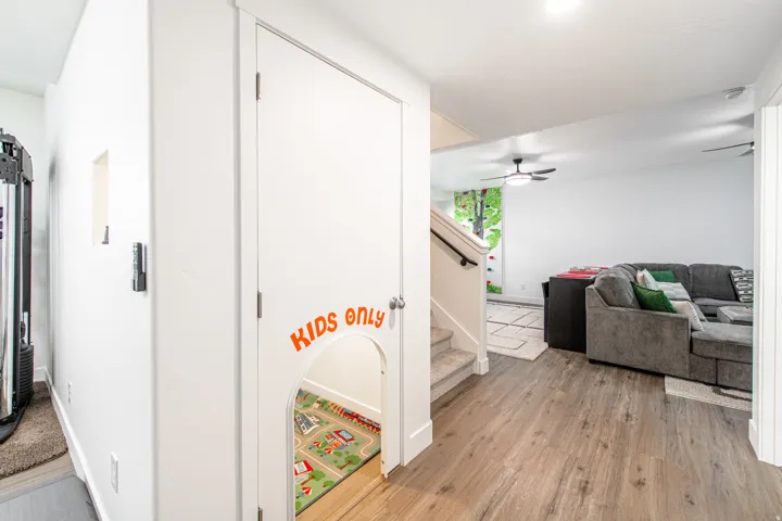 Wood-finish flooring, white walls, recessed lighting, and a staircase with a dark handrail