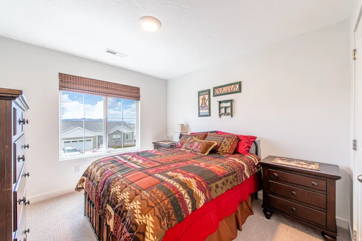 Carpeted flooring, white painted walls, and a large window with a woven shade