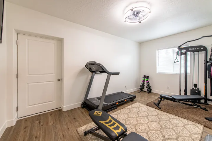 Wood-finish flooring with white baseboards, a two-panel interior door, and a ceiling-mounted light fixture